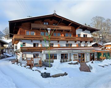 Ein charmantes Hotel im Alpenstil, umgeben von schneebedeckten Landschaften. Die Fassade ist aus Holz und verleiht dem Gebäude eine gemütliche Atmosphäre.