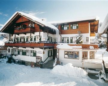 A charming house in classic Alpine style, surrounded by snow. The atmosphere is cozy and inviting.