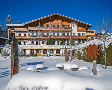 A charming building in Alpine style, surrounded by snow-covered landscapes. The clear blue sky complements the wintry scenery.