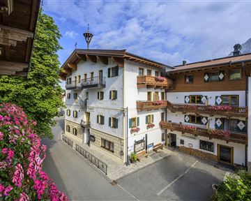 A picturesque village with traditional buildings and blooming flowers. The clear air and the view of the mountains create an inviting atmosphere.