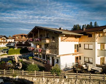 Ein charmantes Hotel mit traditioneller Architektur und gemütlichen Balkonen. Umgeben von einer malerischen Landschaft und grünen Pflanzen.