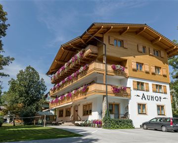 A charming wooden building with balconies and colorful flowers. Surrounded by lots of greenery in a peaceful setting.