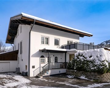 Ein modernes Haus mit weißer Fassade und einem Balkon. Der Winter hat die Umgebung mit Schnee bedeckt.